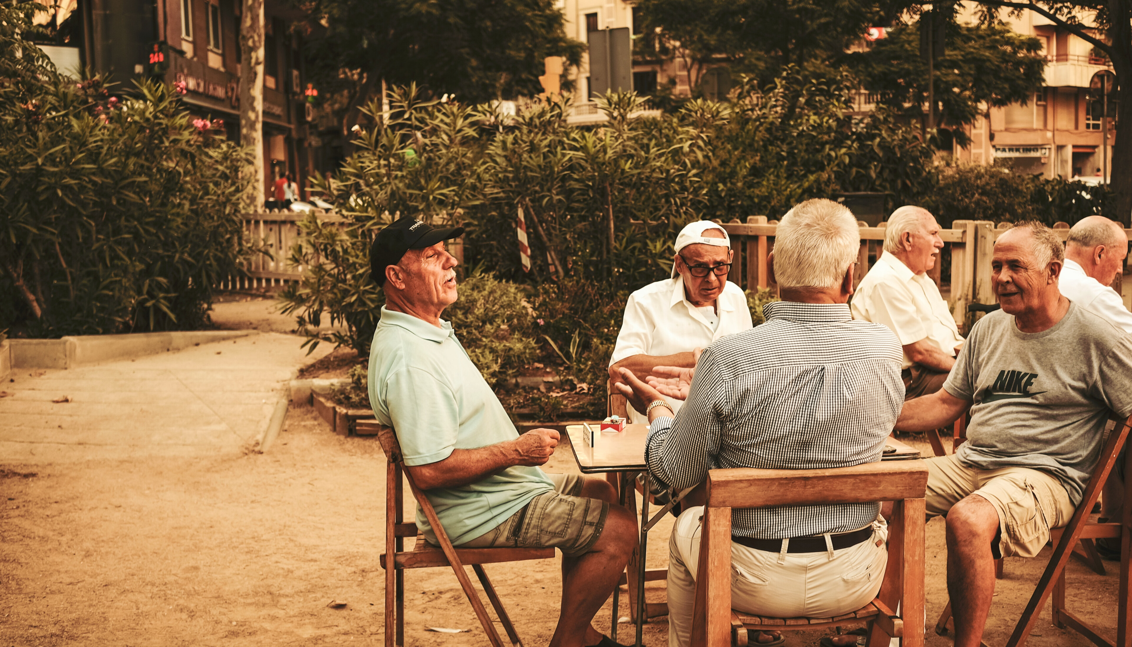 Menschen sitzen bei gutem Wetter draußen am Tisch und unterhalten sich.